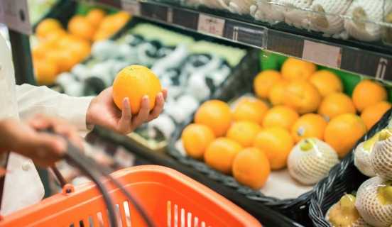 Woman with a shopping basket looking at fruit and vegetables