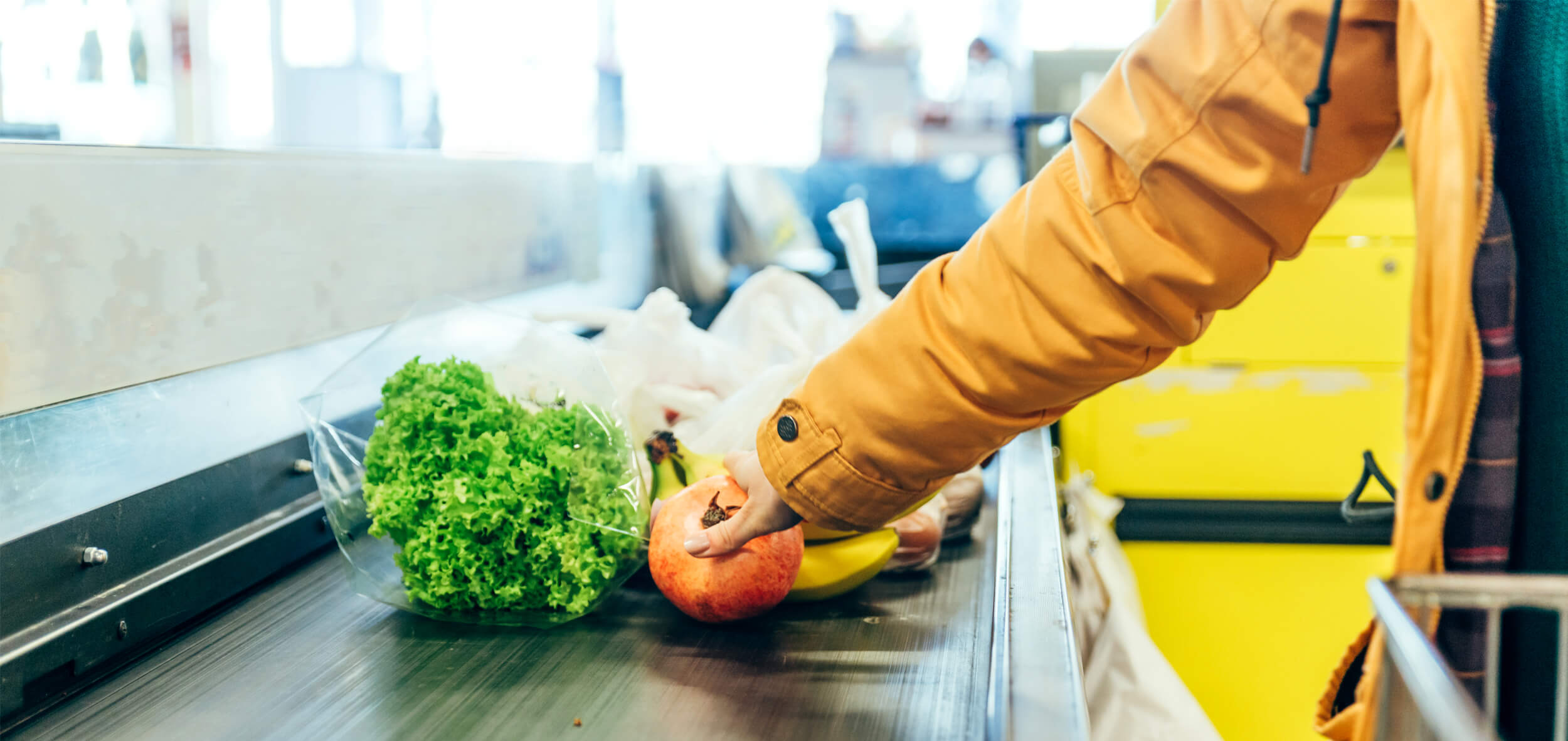 Woman putting food on grocery store conveyor belt
