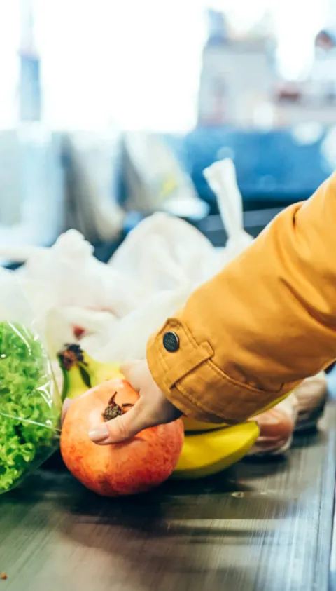 Woman putting food on grocery store conveyor belt